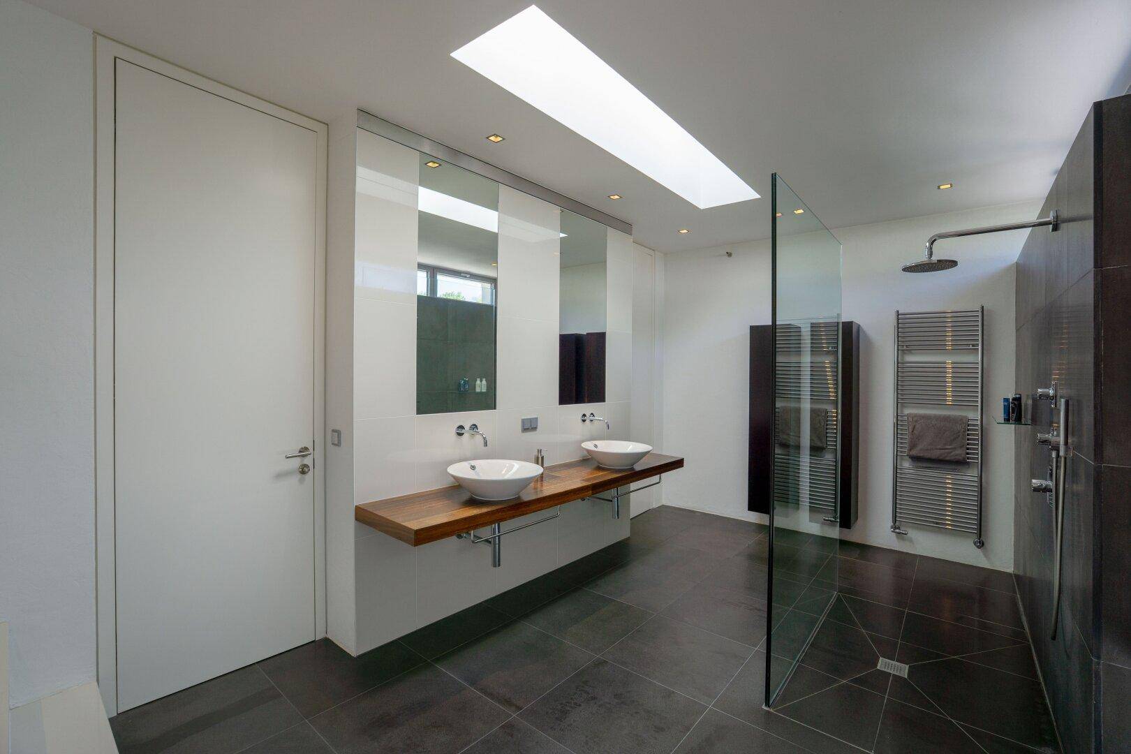 Elegantes Badezimmer mit Doppelwaschbecken, großer Spiegelfläche und beheiztem Handtuchhalter.