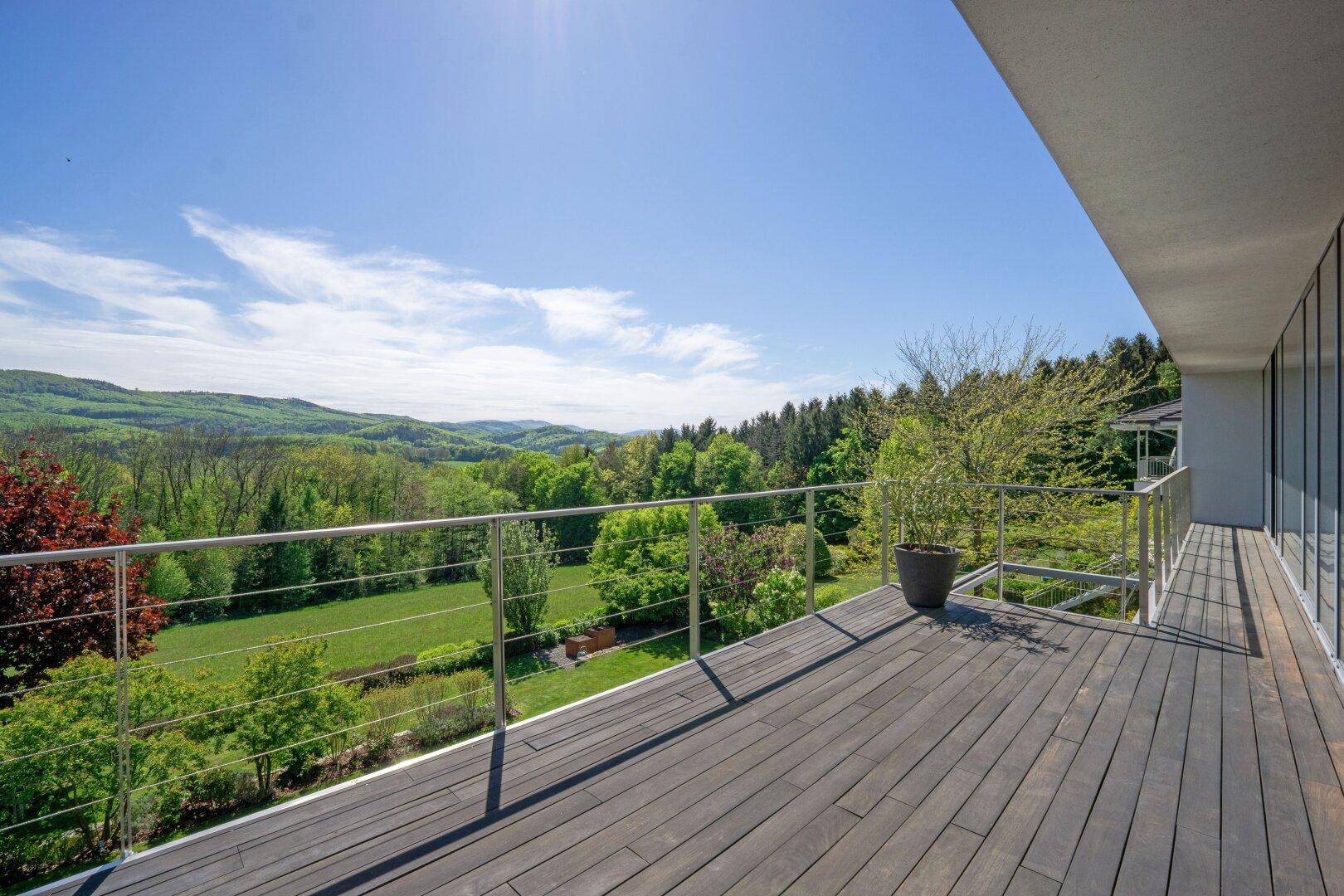 Großer Balkon mit Holzboden und weitem Blick über die grüne Hügellandschaft.