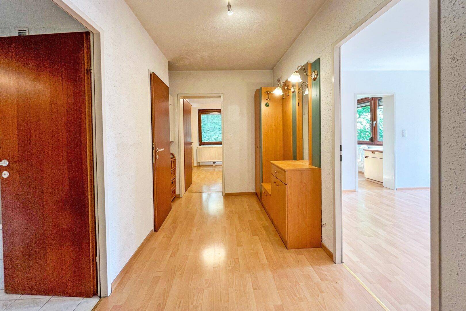 Heller Flur mit Laminatboden und Garderobe, der zu verschiedenen Zimmern führt.