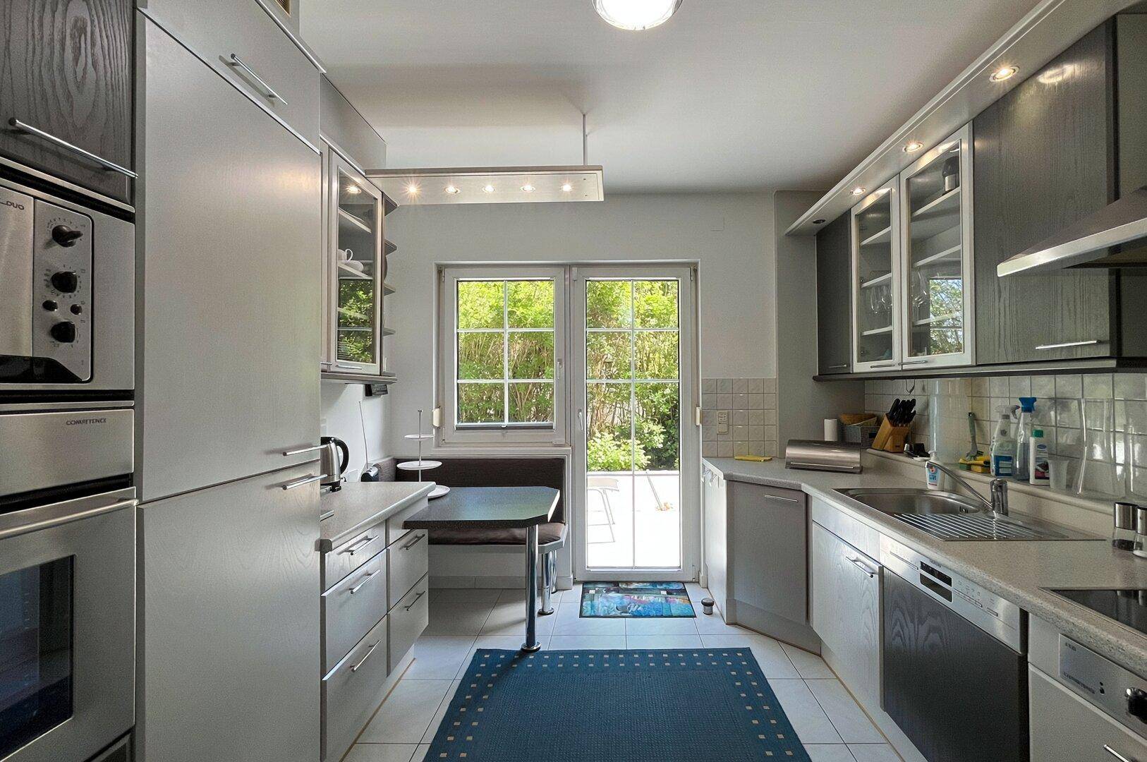 Funktionale Küche mit Einbaugeräten, Essbereich und Fenster zum Garten.