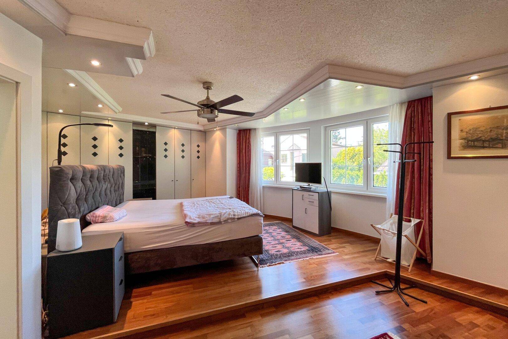 Geräumiges Schlafzimmer mit Holzboden, Einbauschränken und Deckenventilator.