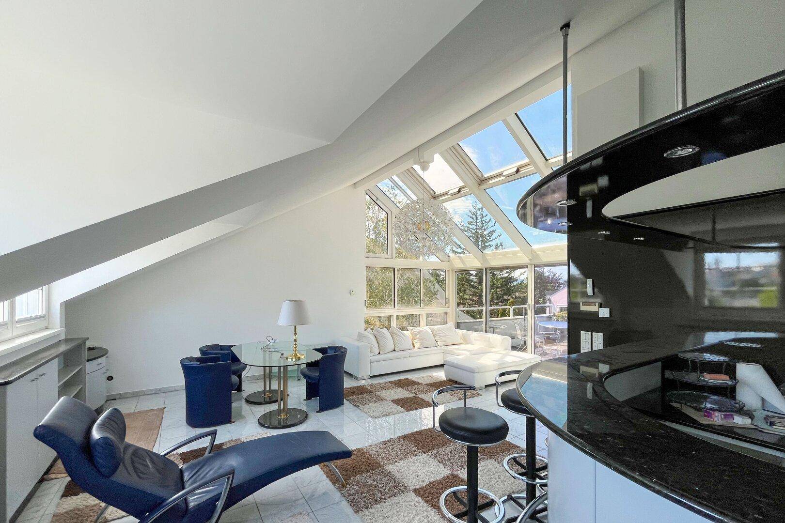 Moderner Wohnbereich mit Bar, Essbereich und beeindruckenden Glasfronten im Dachgeschoss.