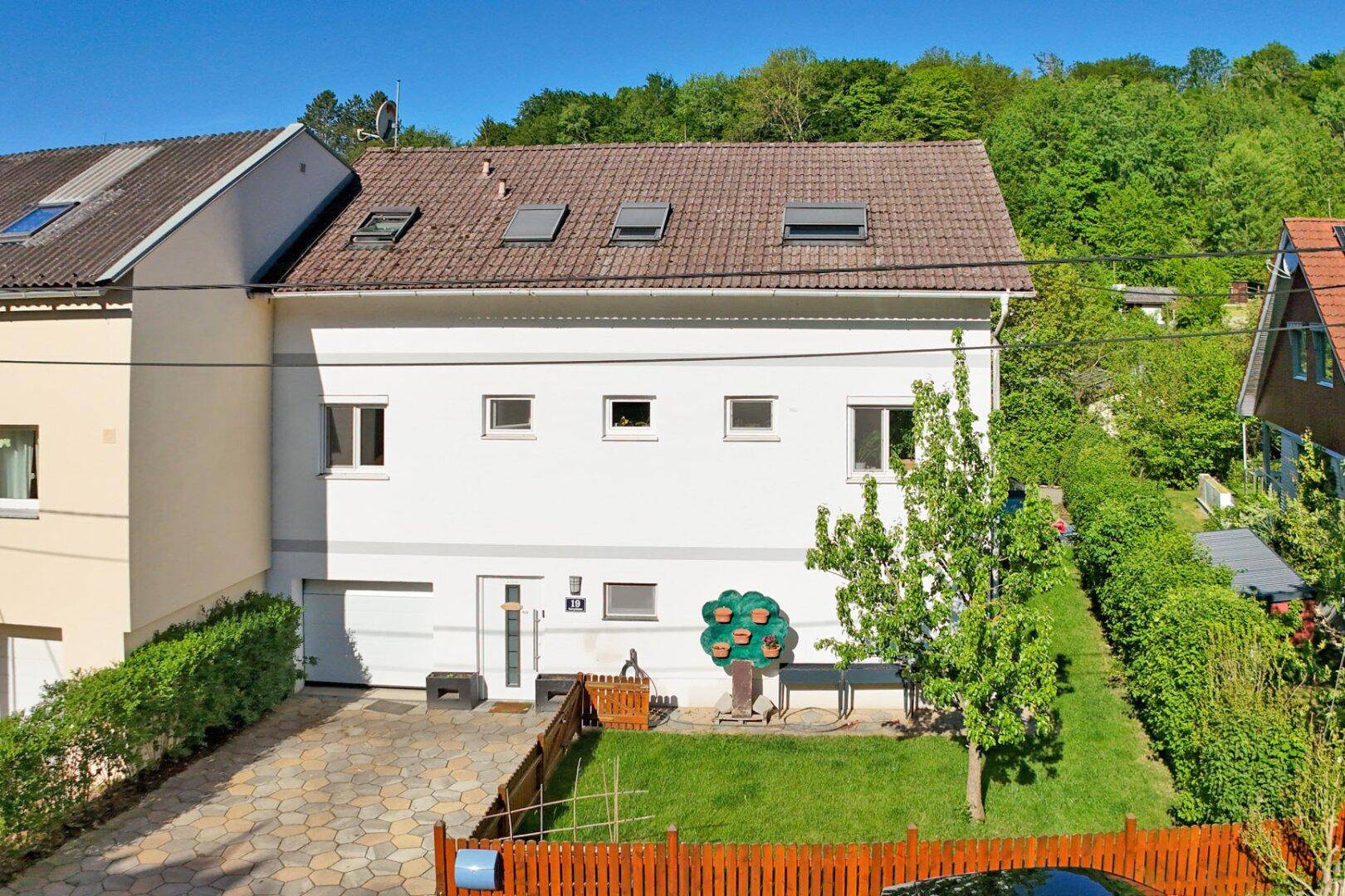 Vorderansicht des Hauses mit gepflasterter Einfahrt, kleinem Vorgarten und Satteldach.