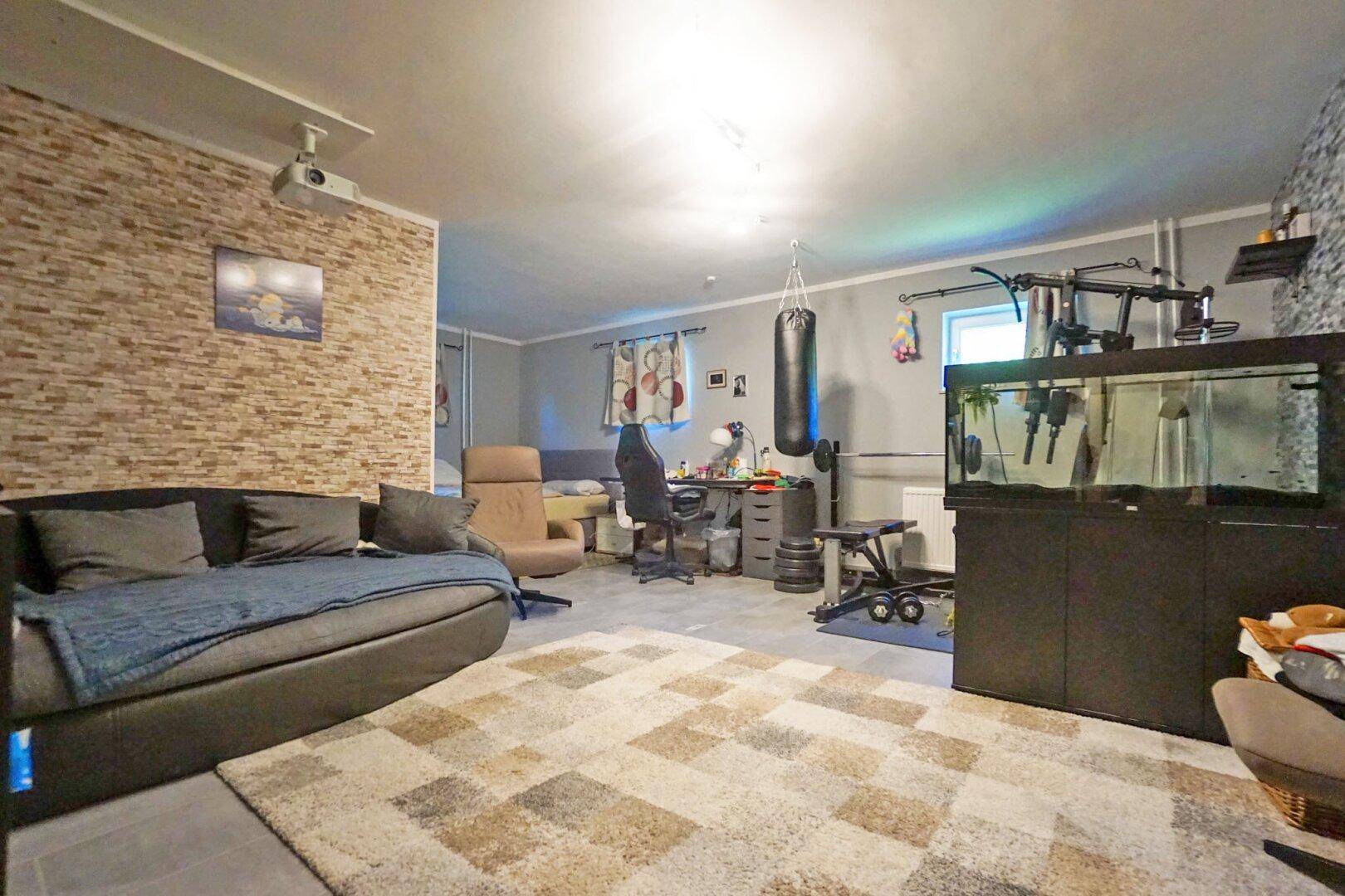 Geräumiger Wohnbereich mit Steinwandakzent, Sofa und Fitnessgeräten.
