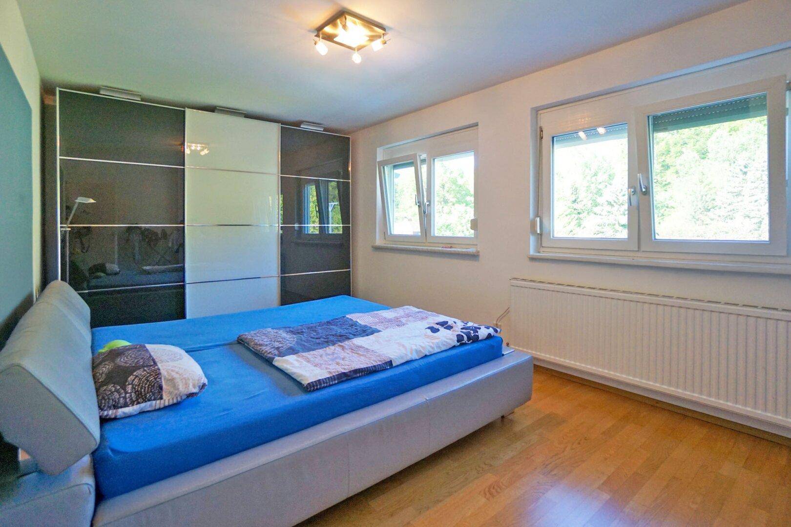Schlafzimmer mit großem Bett, Schiebetürenschrank und Blick ins Grüne.