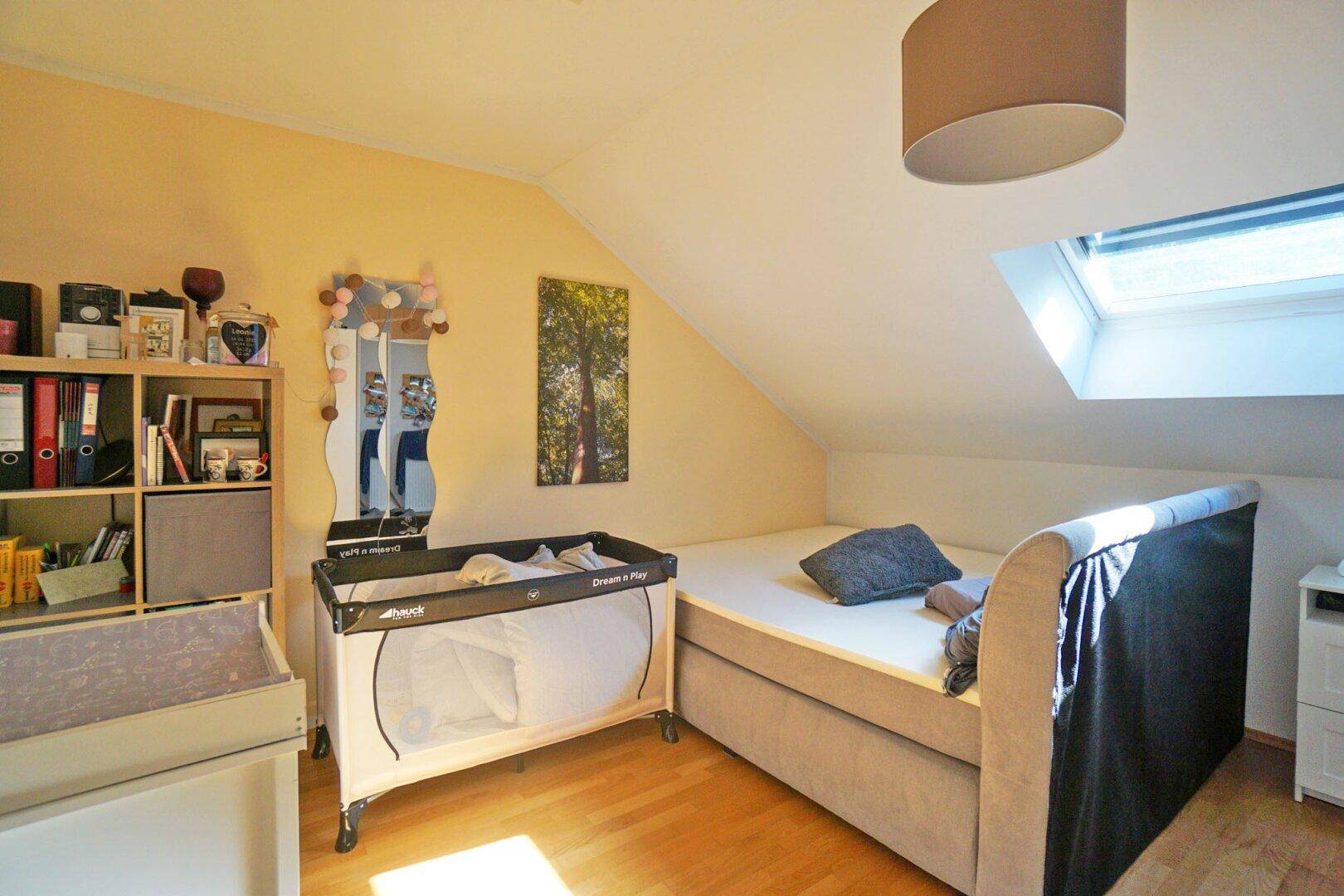 Gemütliches Schlafzimmer im Dachgeschoss mit Dachfenster und Holzboden.