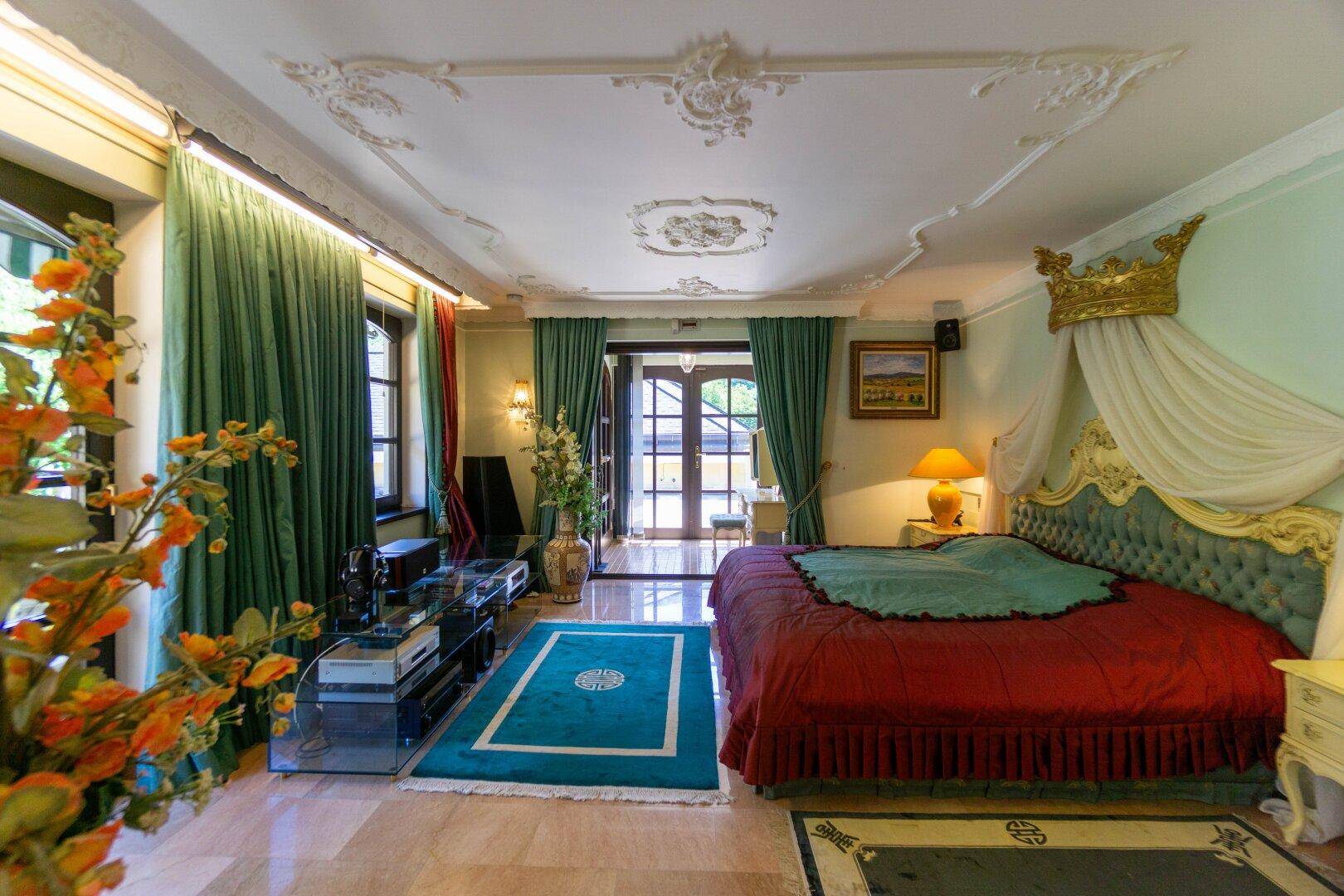 Opulentes Schlafzimmer mit Himmelbett, Marmorboden und Zugang zu einem Balkon.
