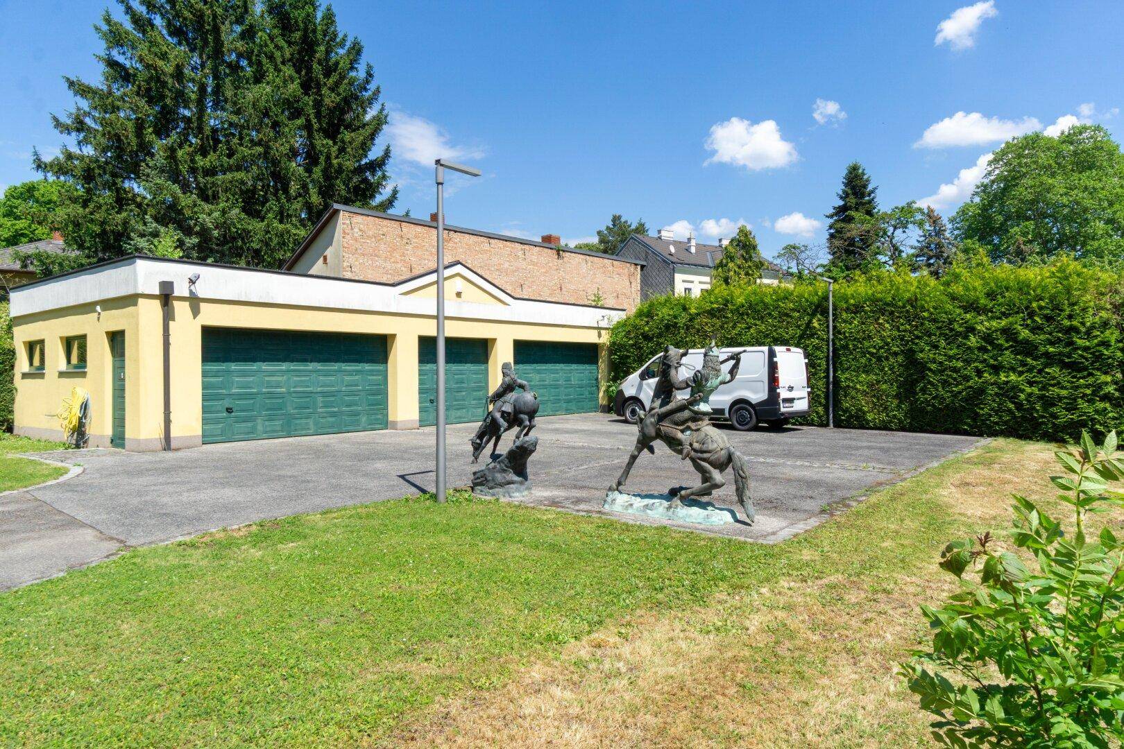 Geräumige Doppelgarage mit grünen Toren und großem Vorplatz für zusätzliche Parkmöglichkeiten.