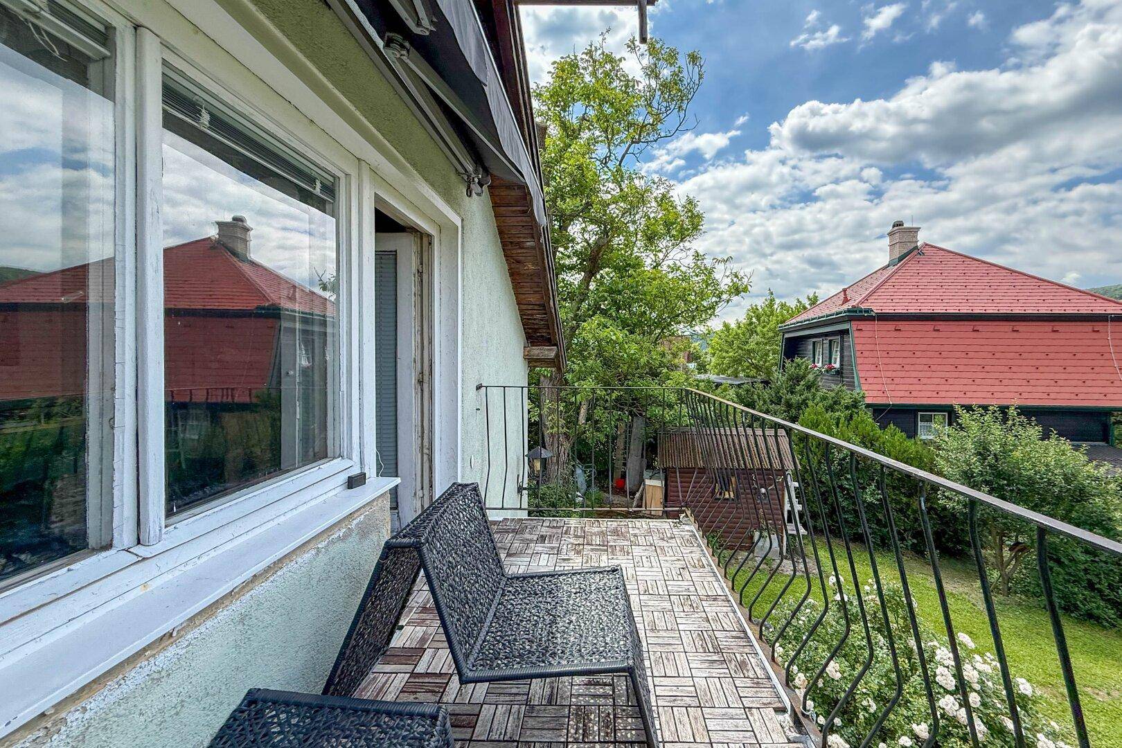 Kleiner Balkon mit Holzboden und Metallgeländer, ausgestattet mit Sitzgelegenheiten und Aussicht.