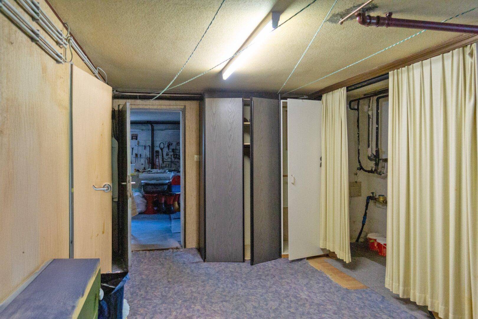 Kellerraum mit mehreren Türen, Schränken und einem Bereich für Haustechnik.