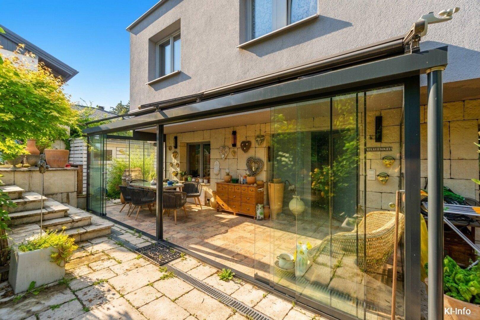 Heller Wintergarten mit Glasfronten, Essbereich und Zugang zum gepflasterten Außenbereich.