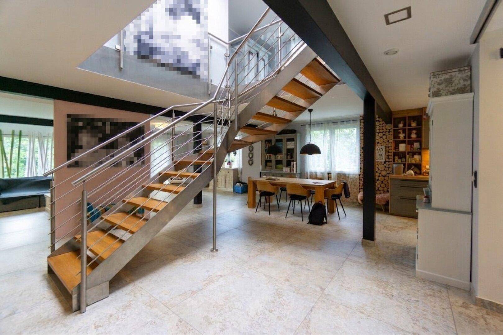 Offener Wohn- und Essbereich mit moderner Treppe und hellem Fliesenboden.