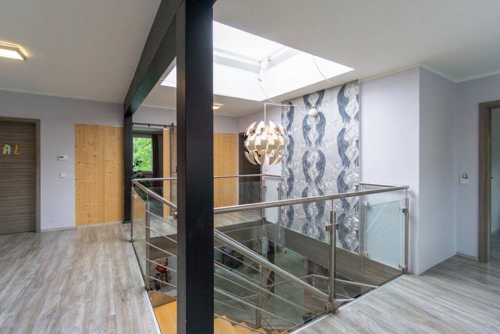 Heller Flur im Obergeschoss mit moderner Treppe, Glasgeländer und Oberlicht.