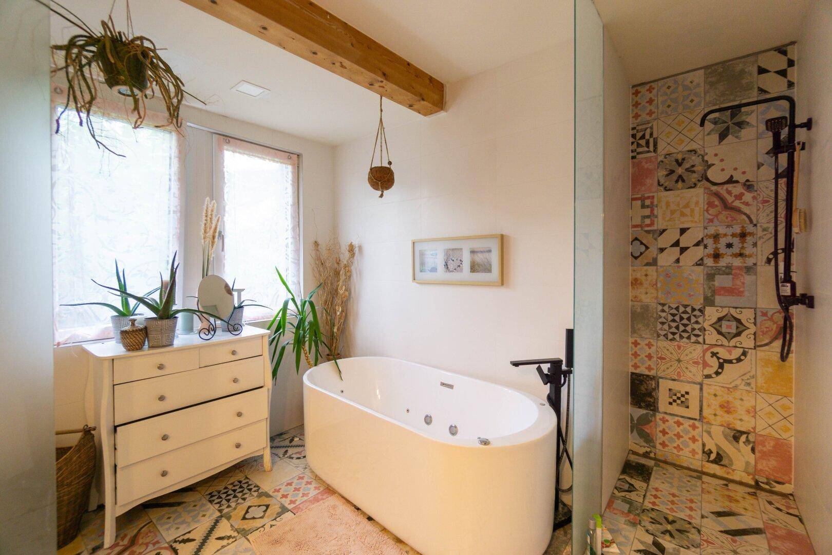 Modernes Badezimmer mit freistehender Badewanne, begehbarer Dusche und farbigen Fliesen.