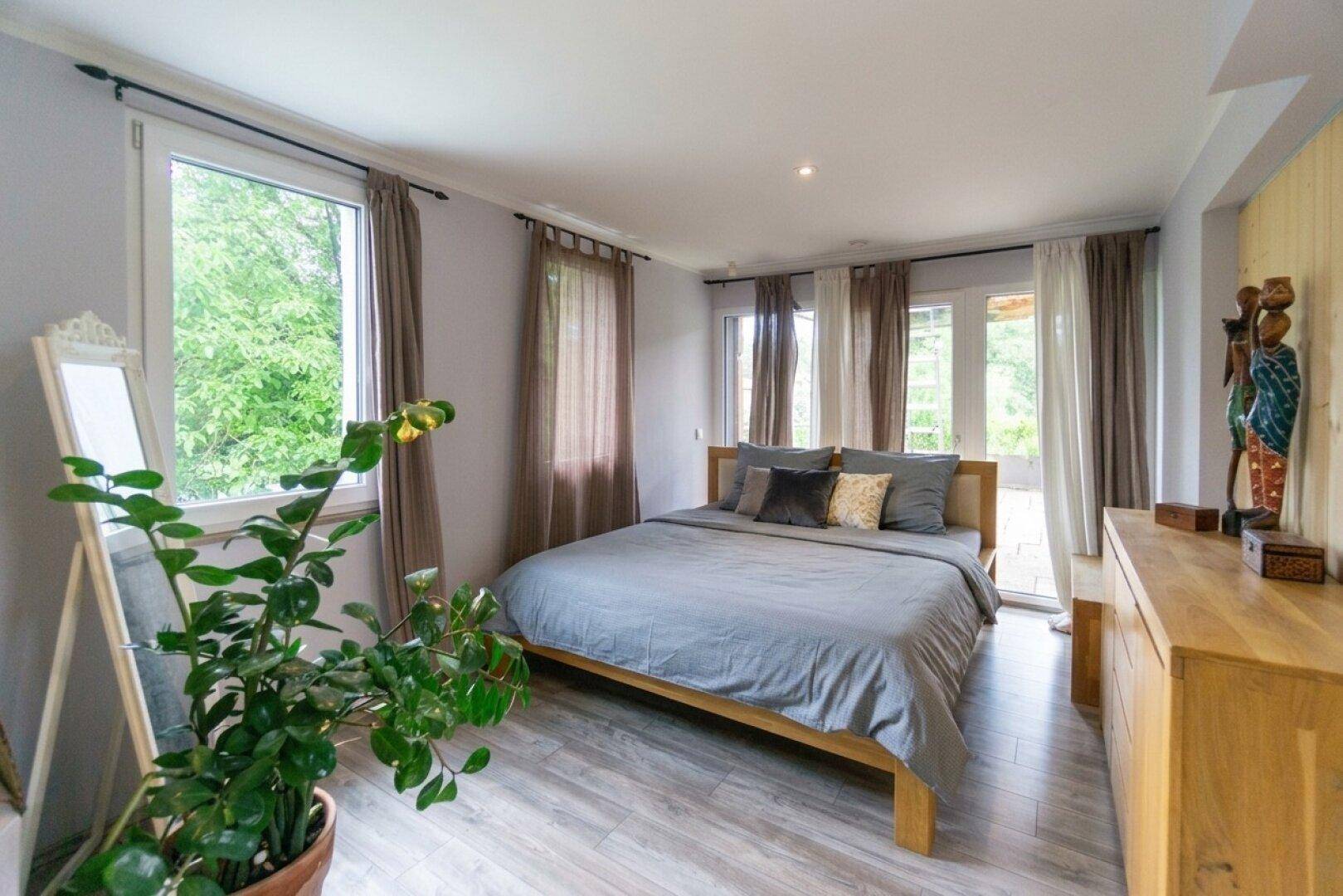 Helles Schlafzimmer mit Doppelbett, Holzboden und Zugang zur Terrasse.