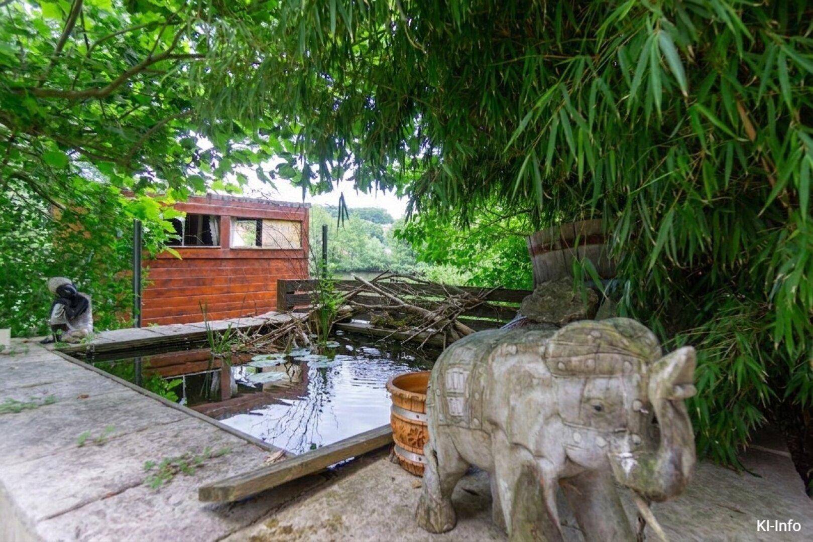 Idyllischer Gartenbereich mit Teich, Bambuspflanzen und Holzskulpturen.