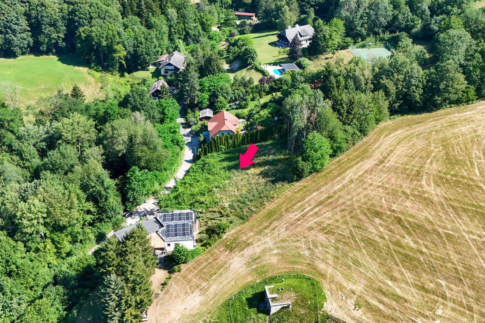 Luftaufnahme eines Grundstücks mit umliegenden Feldern und Wäldern, inklusive Pool und Tennisplatz in der Ferne.