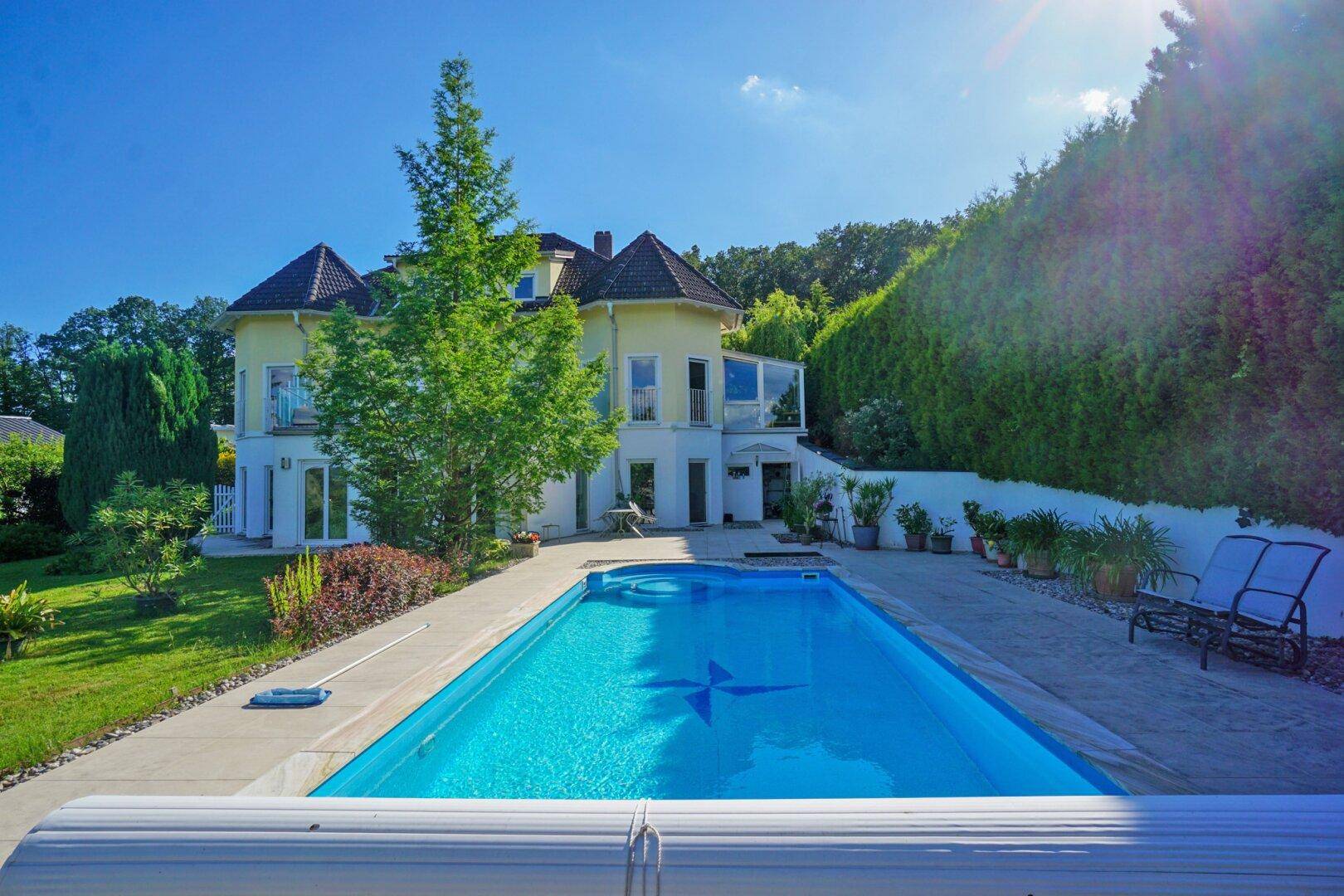 Großzügiger Außenbereich mit privatem Pool und Liegeflächen, umgeben von einem gepflegten Garten.