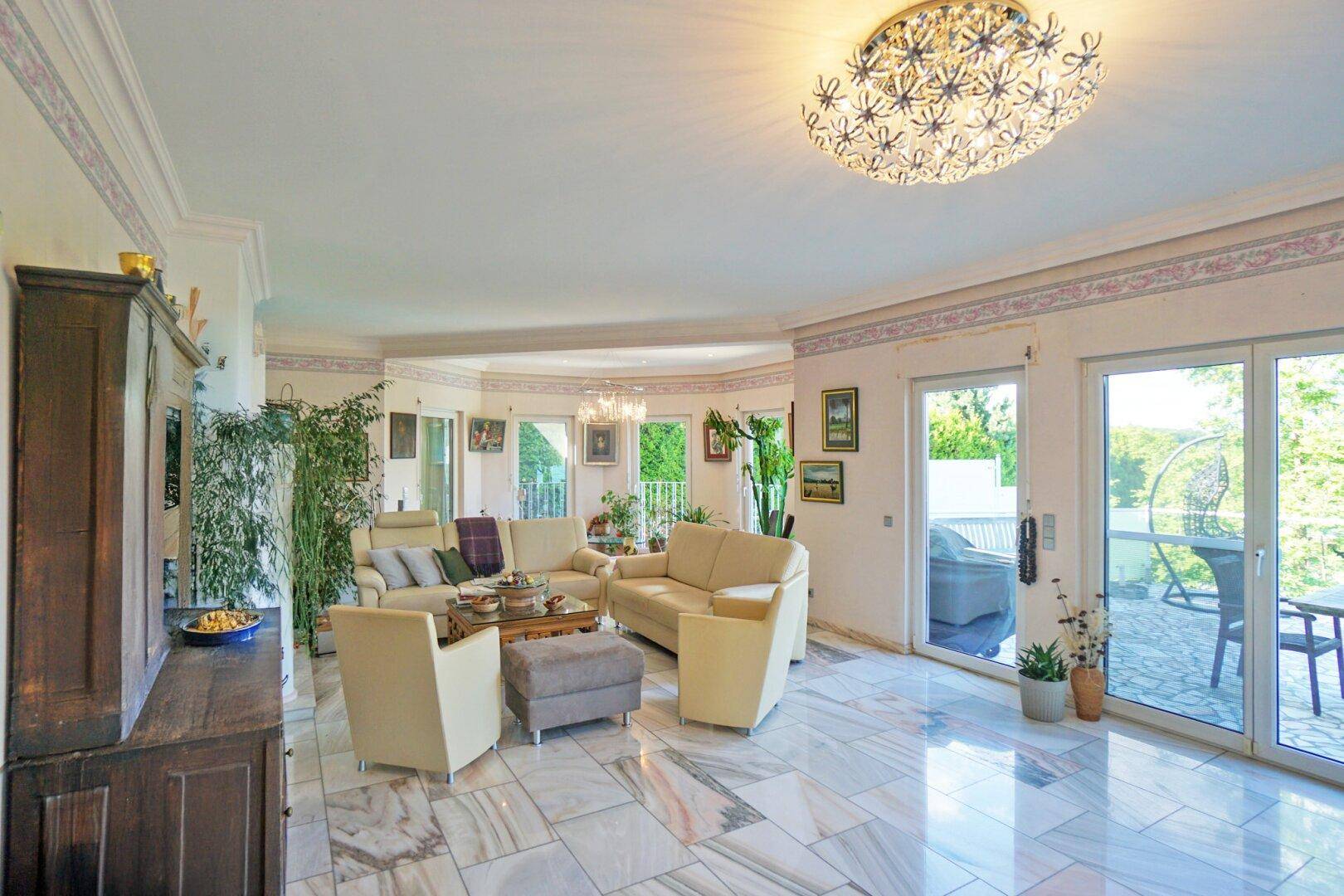 Geräumiges Wohnzimmer mit edlem Marmorboden, gemütlichen Sofas und Zugang zur Terrasse.