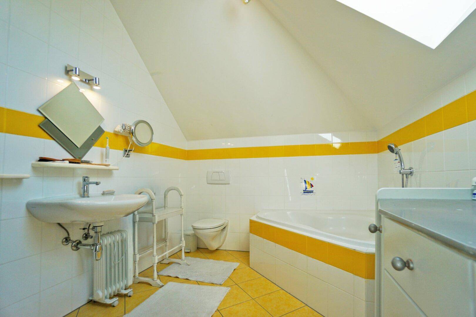 Funktionales Badezimmer mit Badewanne, Fliesenboden und farbigen Akzenten.