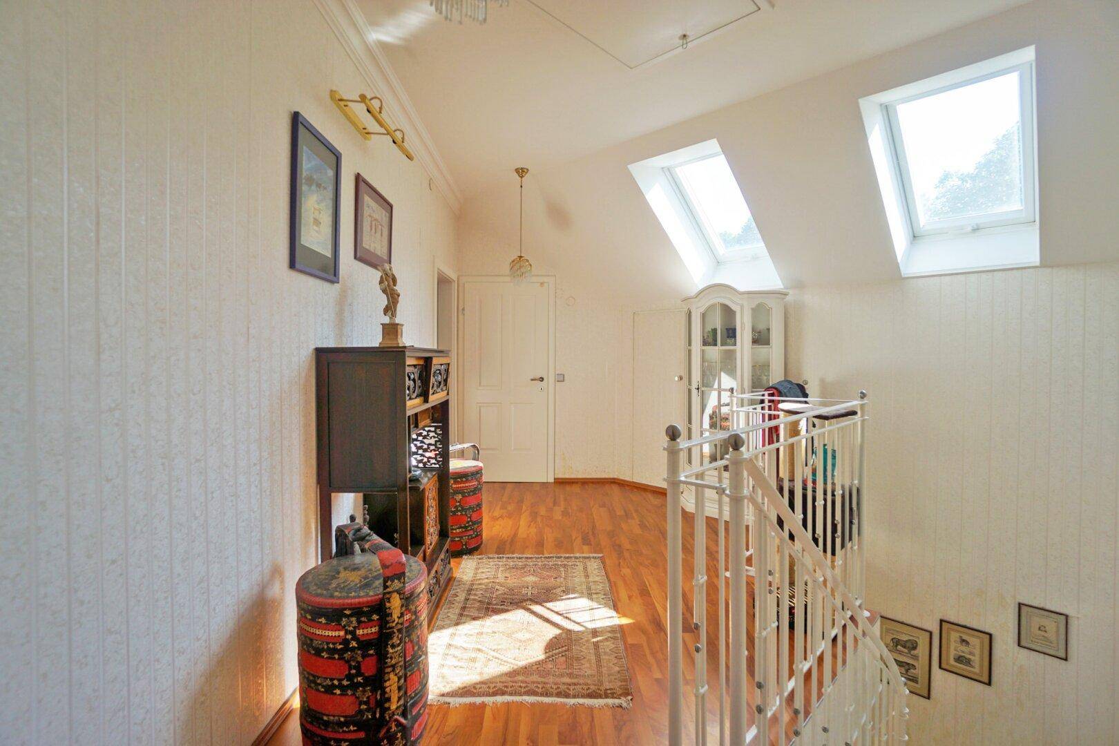 Heller Flur im Obergeschoss mit Holzboden, Dachfenstern und Zugang zu weiteren Räumen.