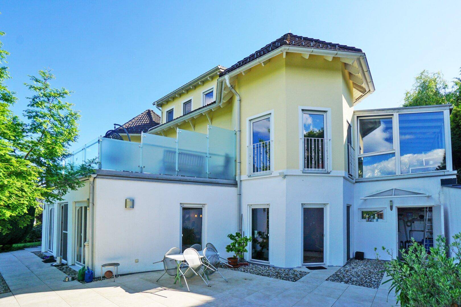 Seitenansicht des Hauses mit kleiner Terrasse im Erdgeschoss und einer weiteren im Obergeschoss.