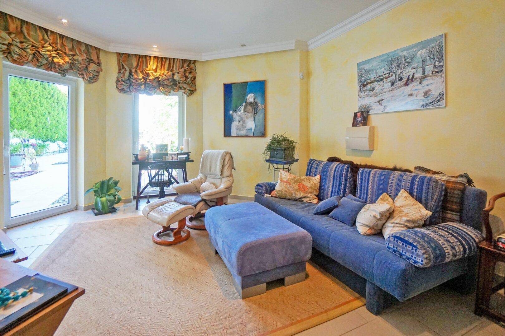 Komfortables Wohnzimmer mit blauem Sofa, Teppich und direktem Zugang zum Garten.