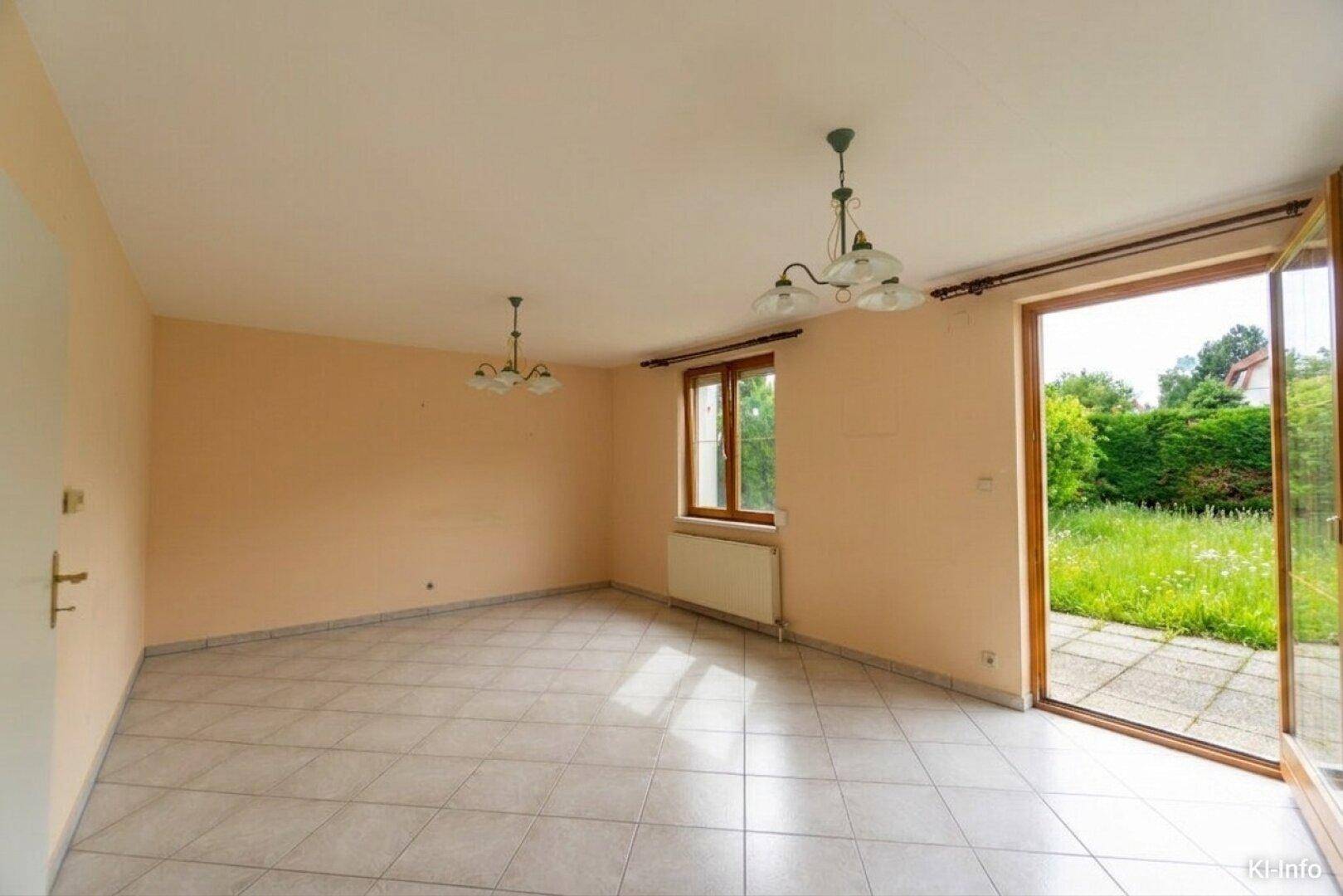 Helles Wohnzimmer mit Fliesenboden und direktem Zugang zum Garten, ideal für Familien.