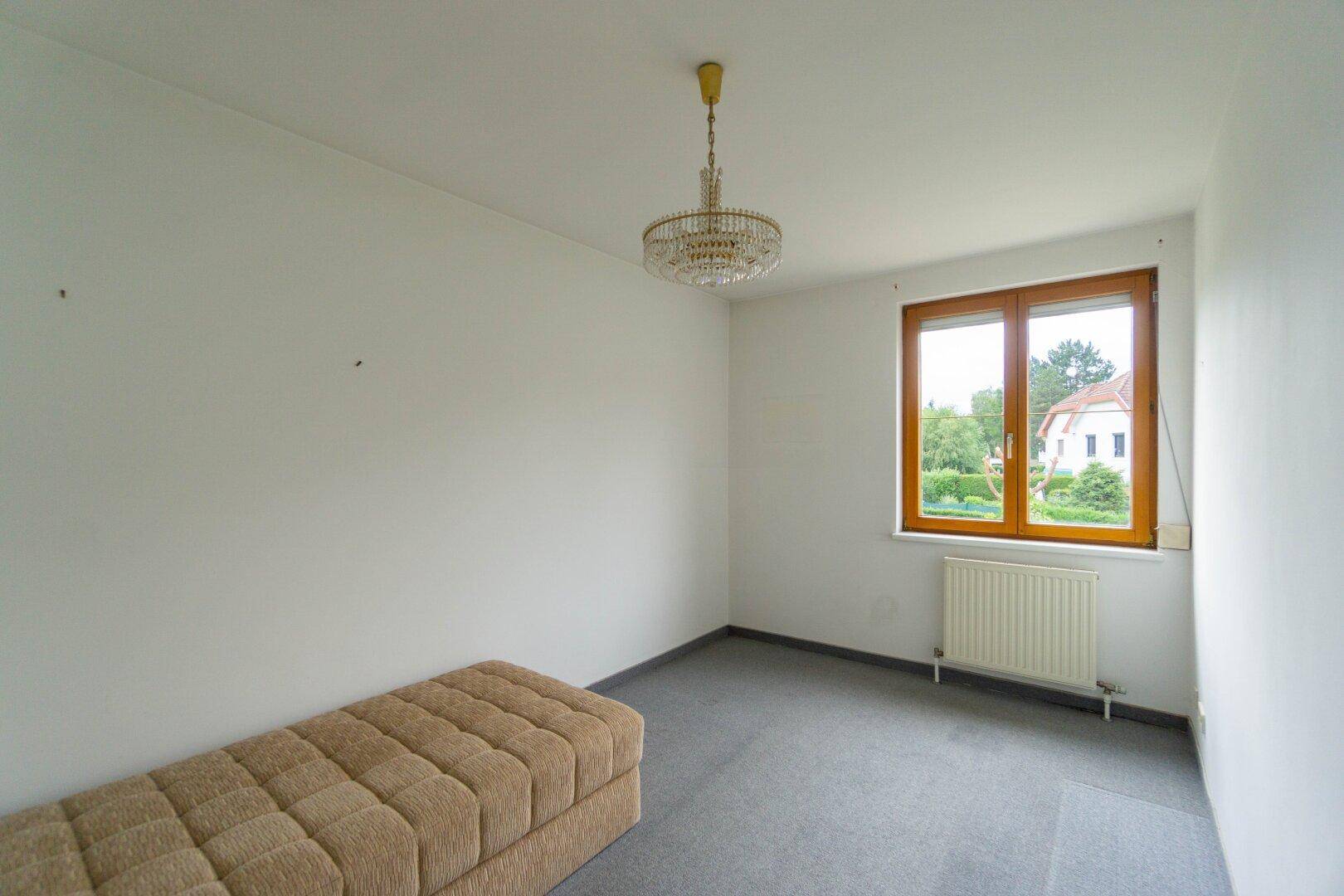 Helles Schlafzimmer mit Teppichboden und großem Fenster, bietet viel Tageslicht.