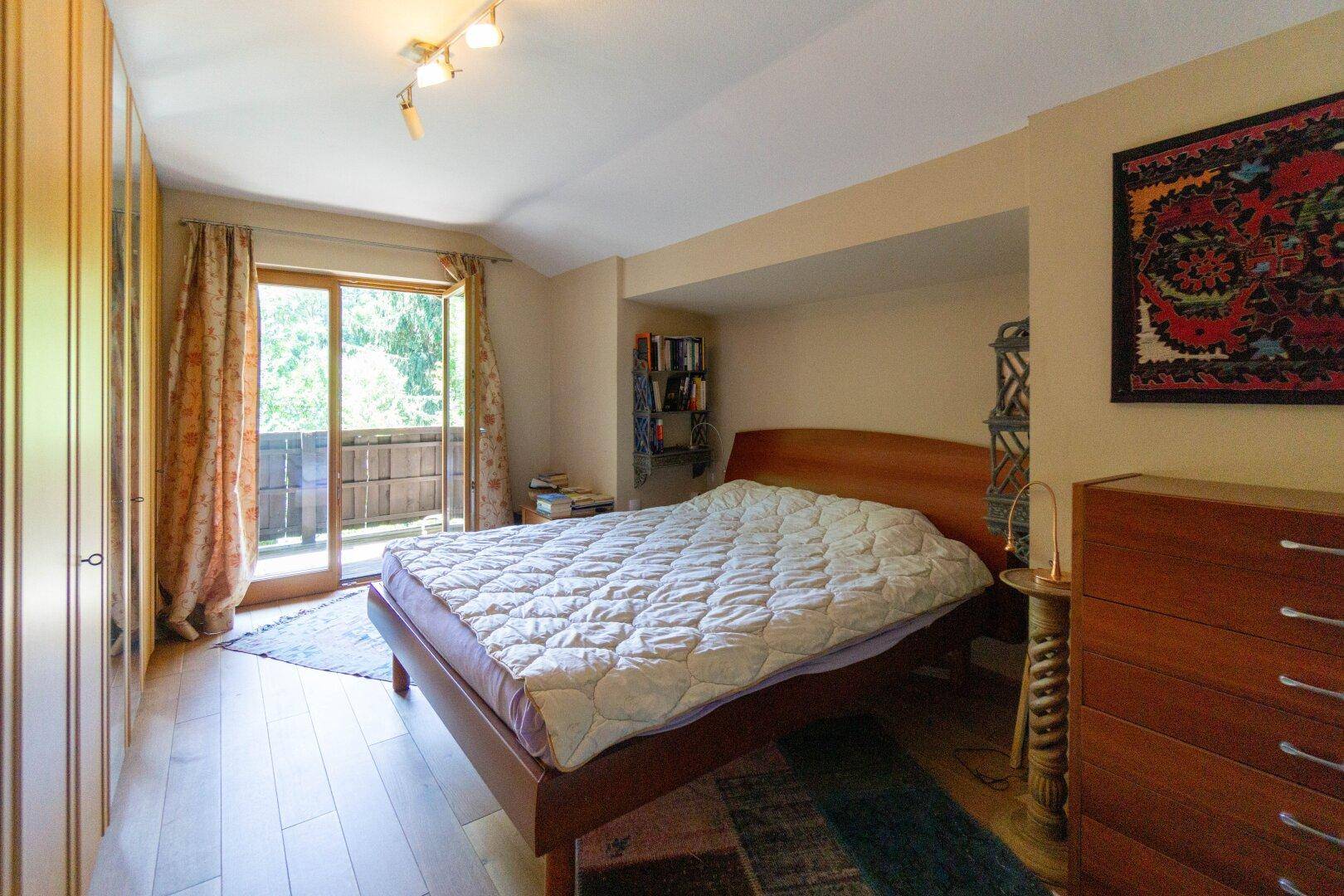 Schlafzimmer mit Holzboden, Einbauschränken und direktem Zugang zu einem privaten Balkon.