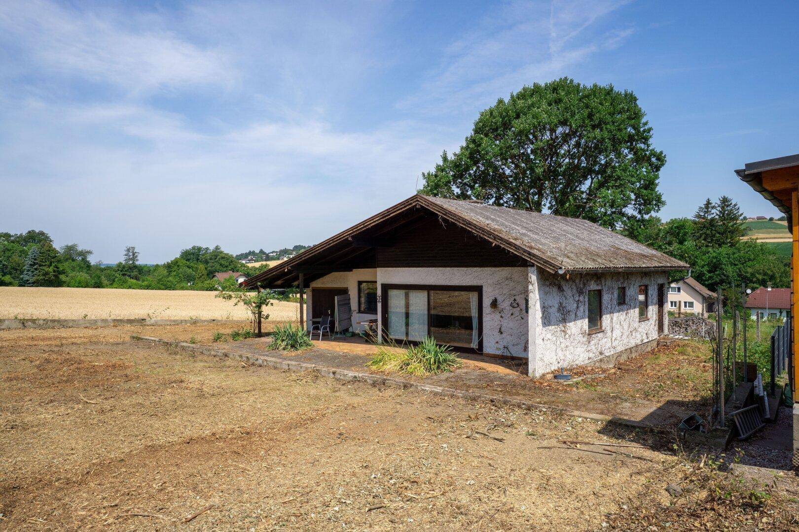 Einfamilienhaus mit weitem Blick über Felder und ländliche Landschaft unter blauem Himmel.