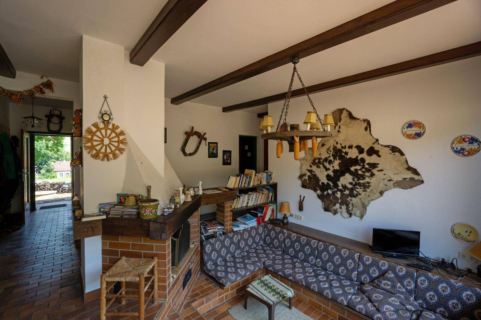 Gemütliches Wohnzimmer mit Kamin, Holzbalken und rustikaler Einrichtung.