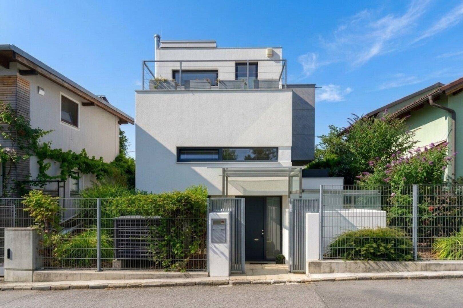 Vorderansicht eines modernen Hauses mit klaren Linien, Eingangsbereich und Dachterrasse.