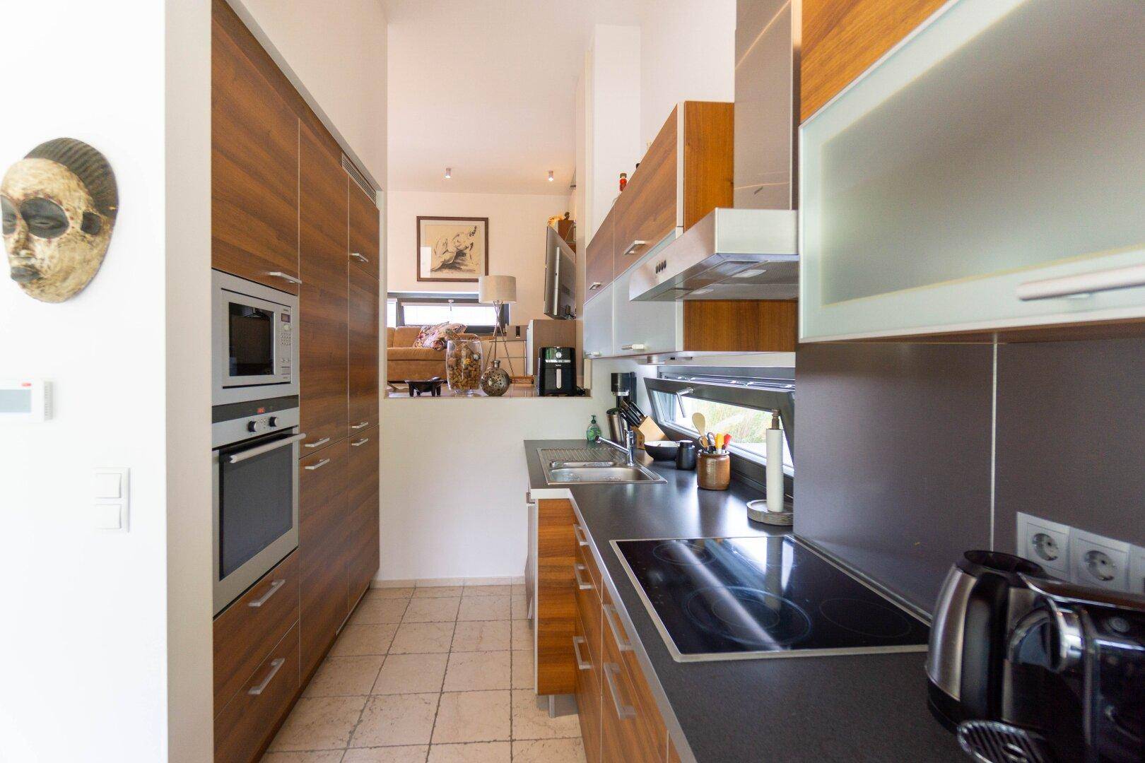 Moderne Einbauküche mit Holzfronten, Induktionskochfeld und integrierten Geräten.