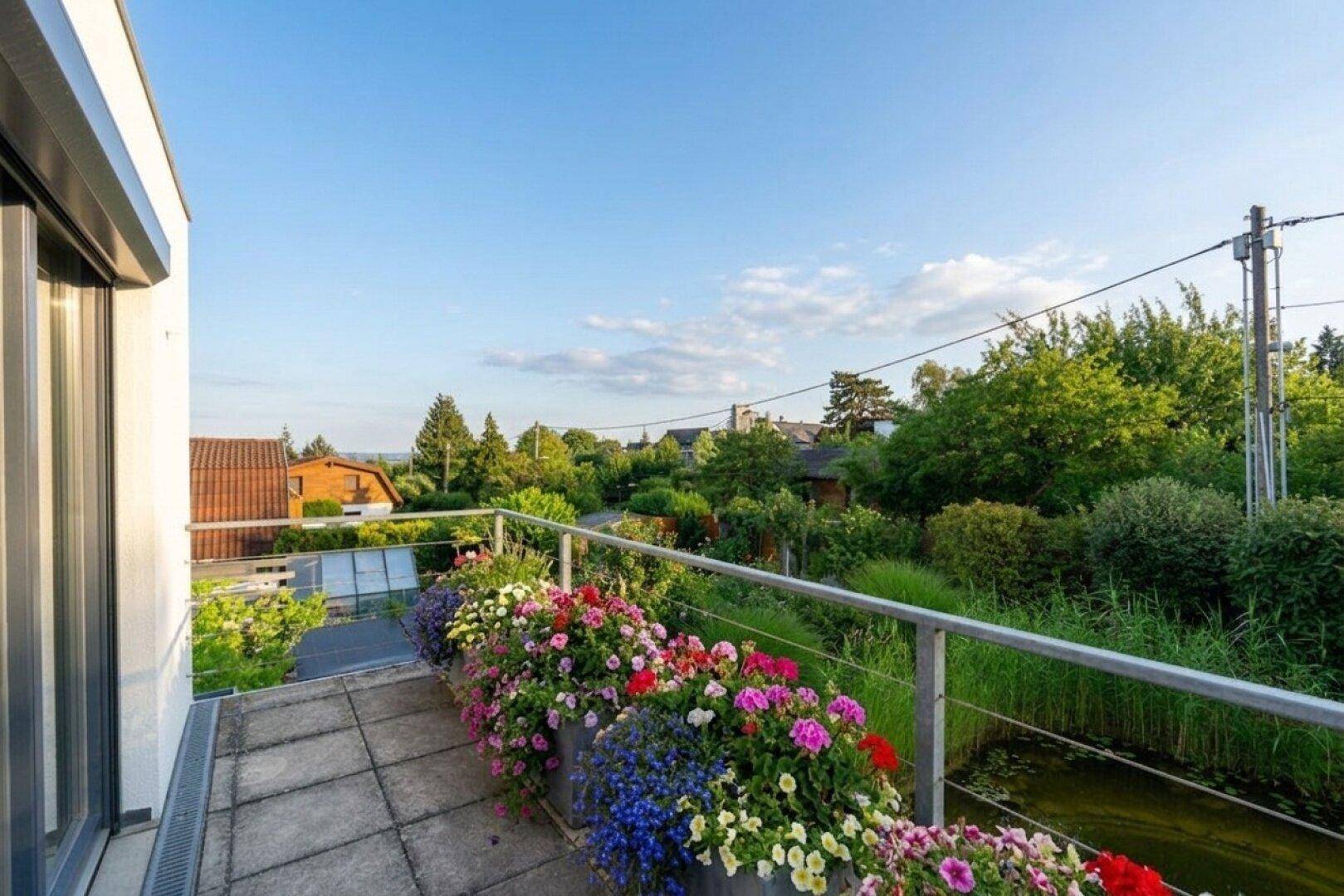 Geräumiger Balkon mit Blumenkästen und weitem Blick über die grüne Nachbarschaft.