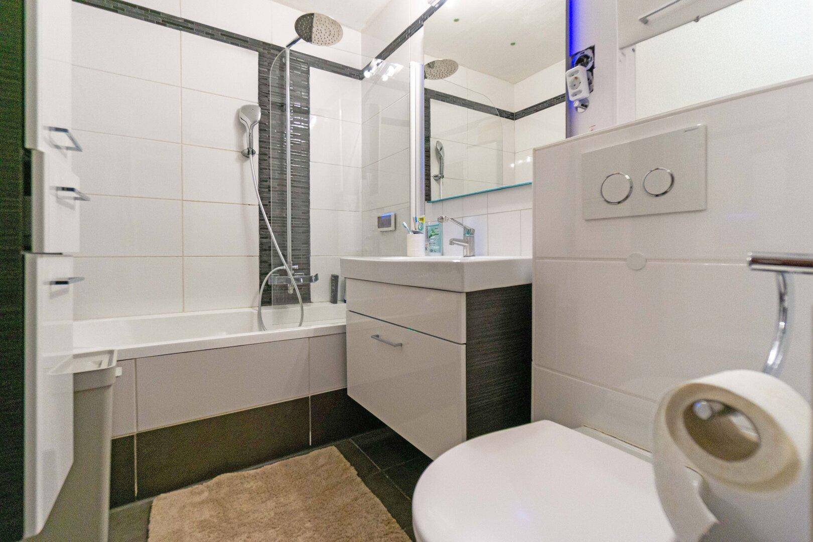 Modernes Badezimmer mit Badewanne, Regendusche, wandhängendem WC und stilvollen Fliesen.