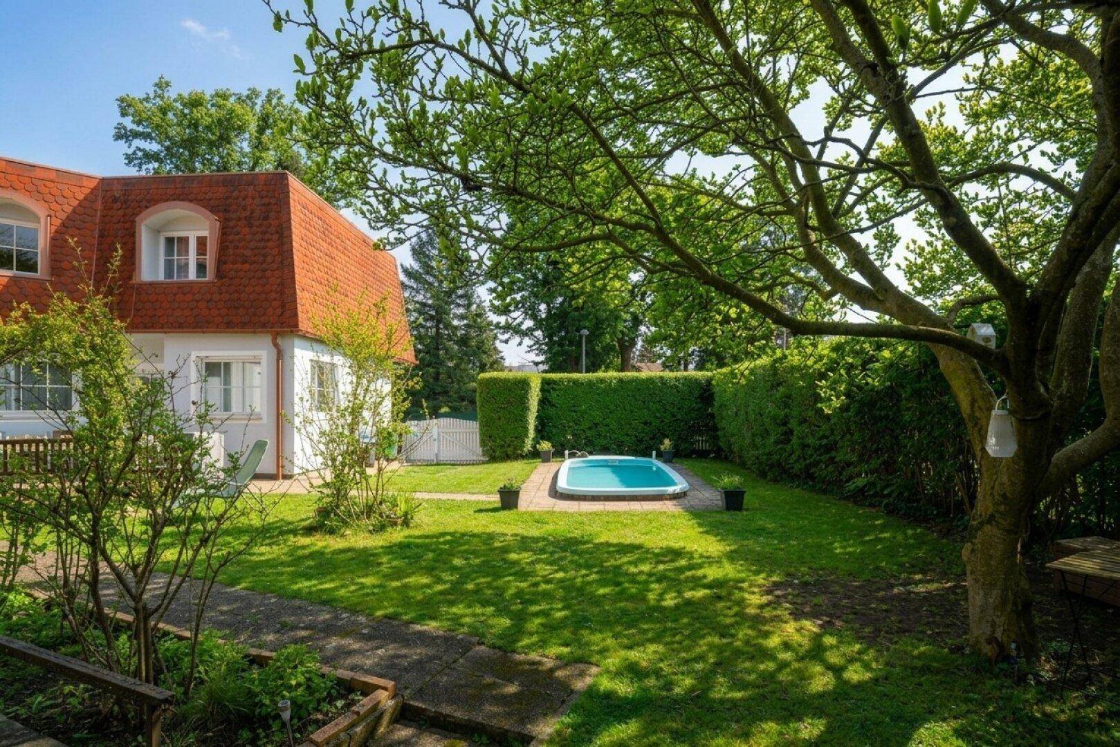 Gepflegter Garten mit kleinem Pool, Rasenfläche und hohen Hecken.