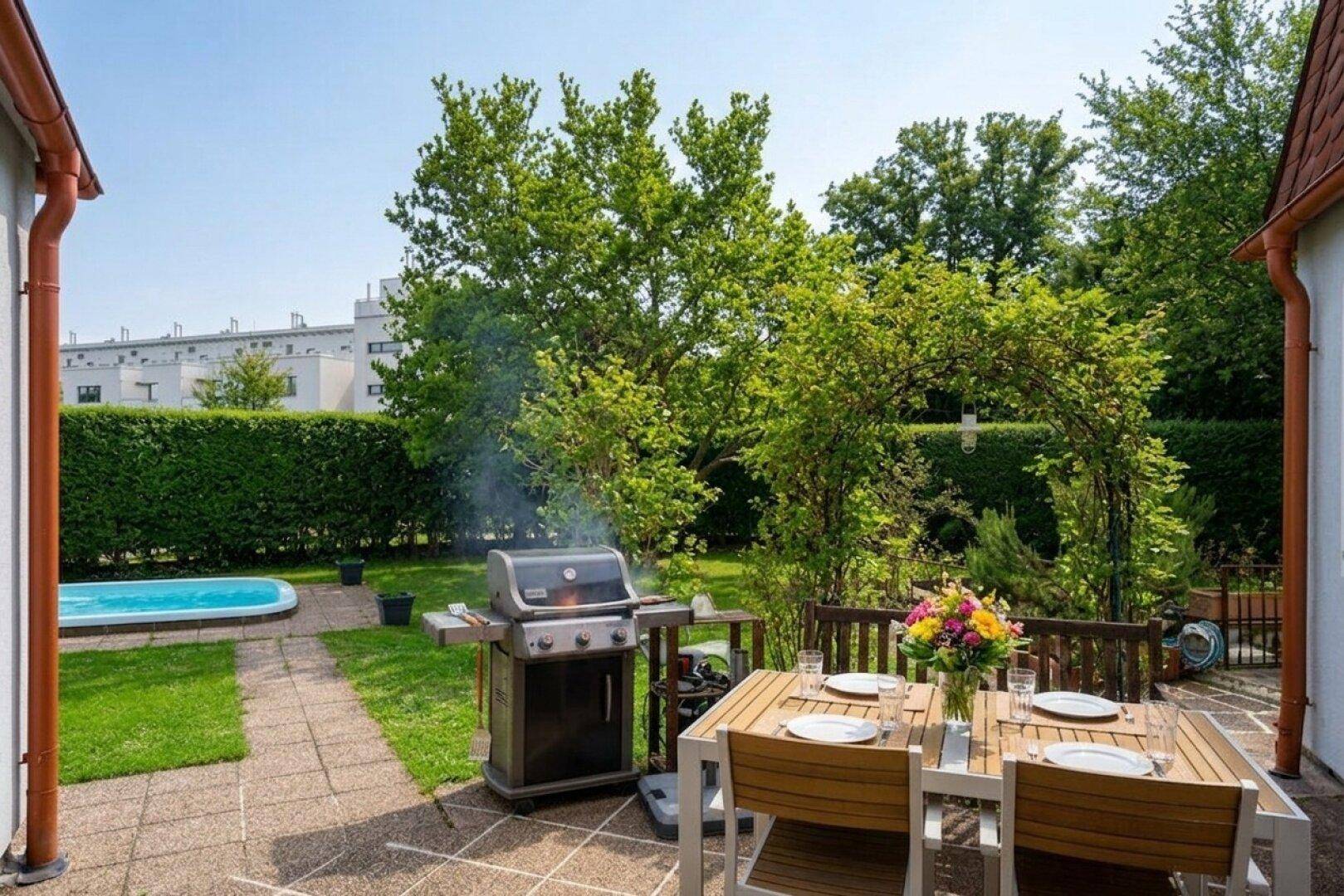 Gemütliche Terrasse mit Esstisch, Grillbereich und Blick auf den Pool im Garten.