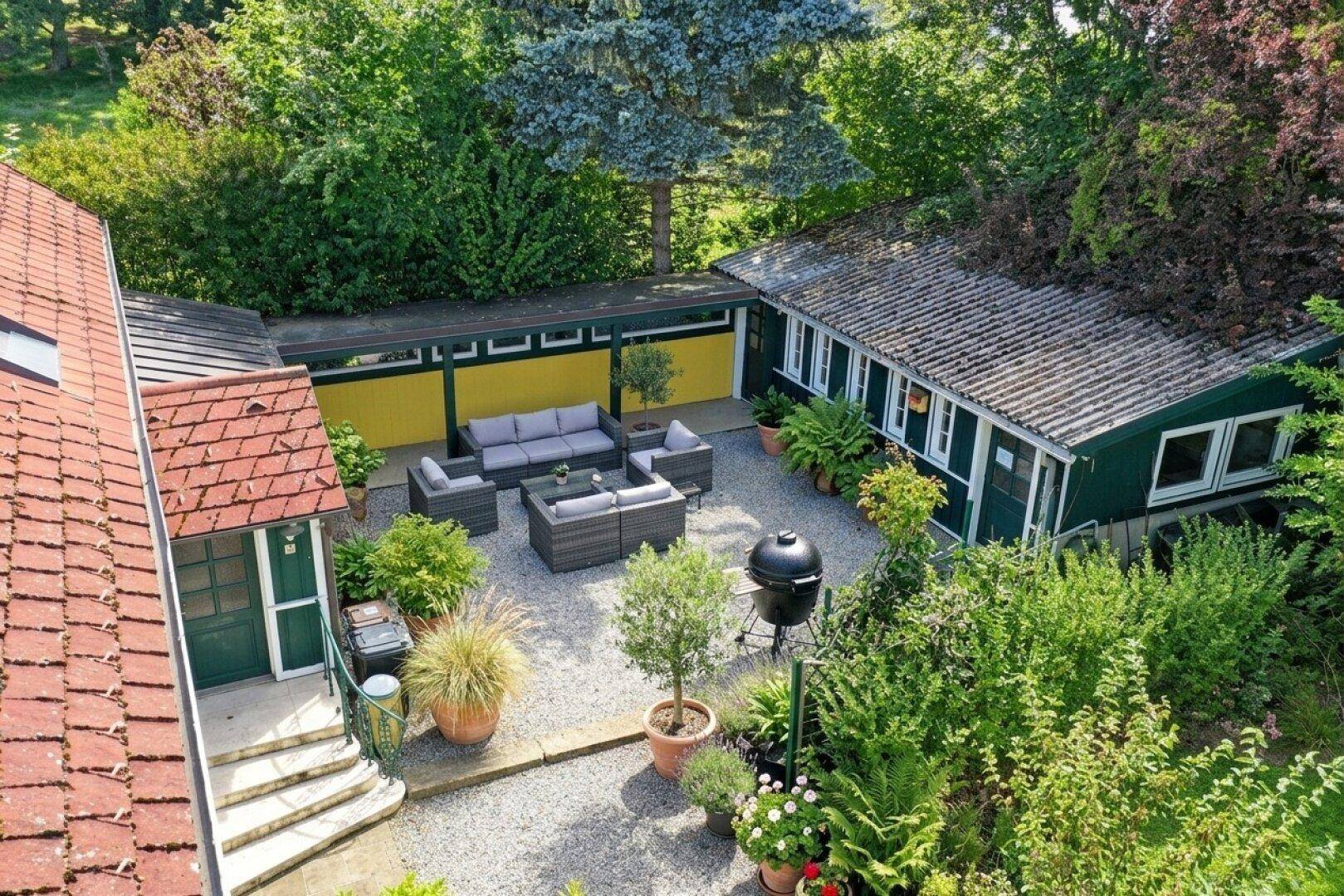 Blick von oben auf den begrünten Innenhof mit moderner Lounge-Sitzgruppe und Grill.