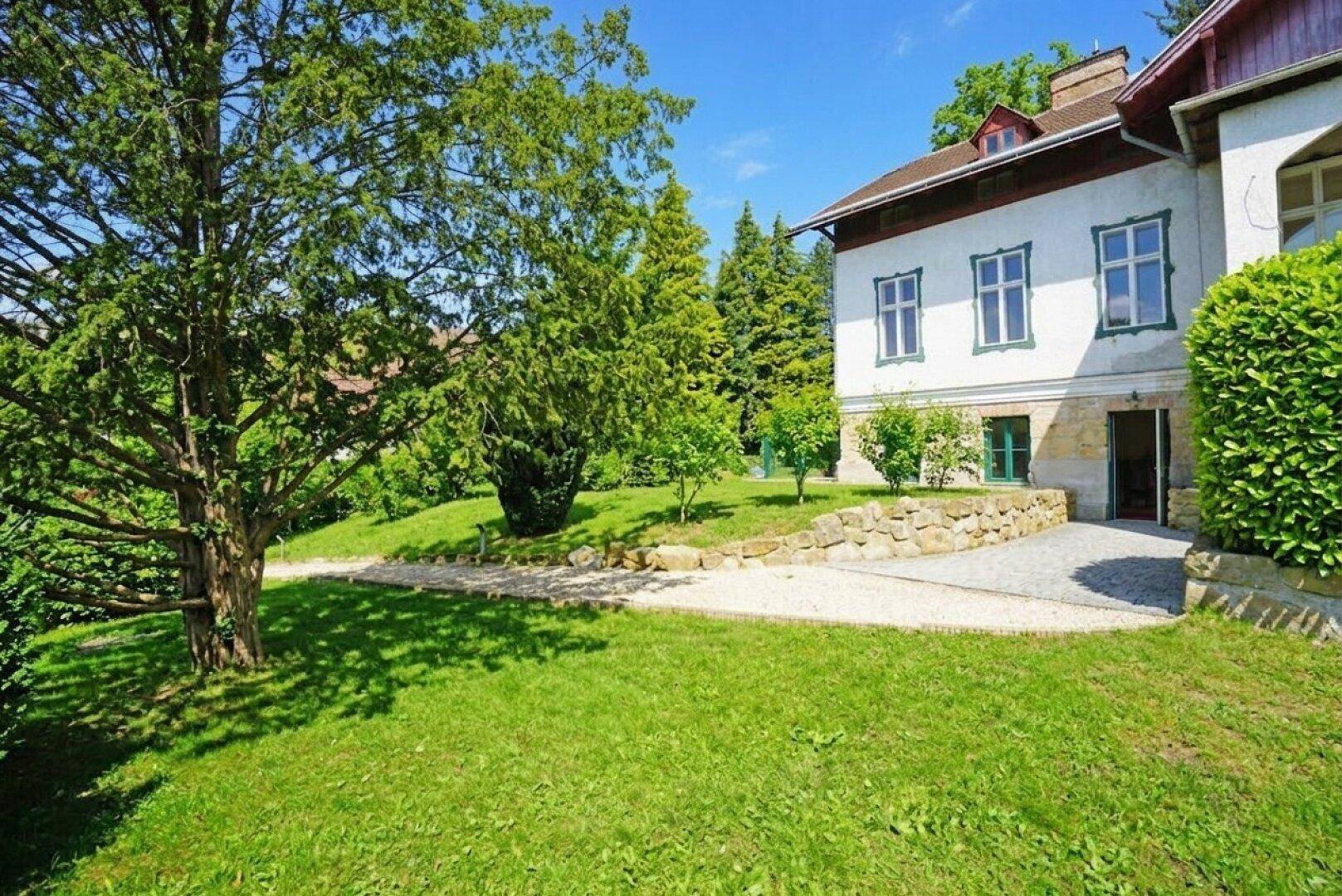 Weitläufiger grüner Gartenbereich mit altem Baumbestand und Blick auf die umliegende Landschaft.