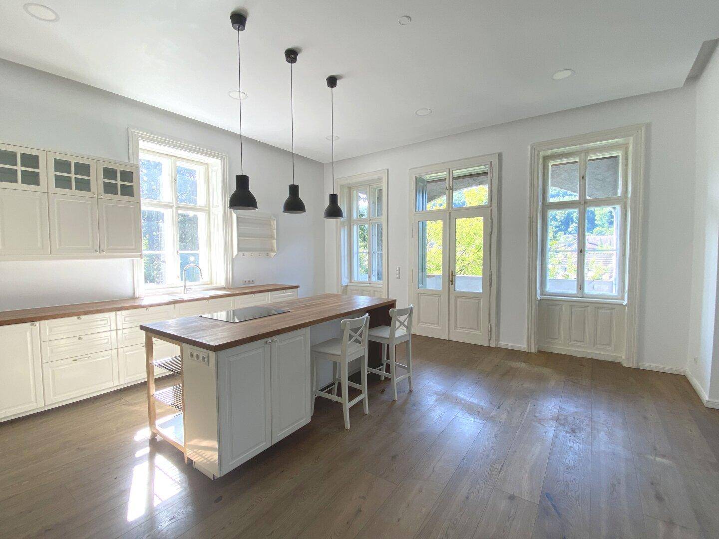 Helle Einbauküche mit Kücheninsel, Holz-Arbeitsplatten und modernen Hängelampen.