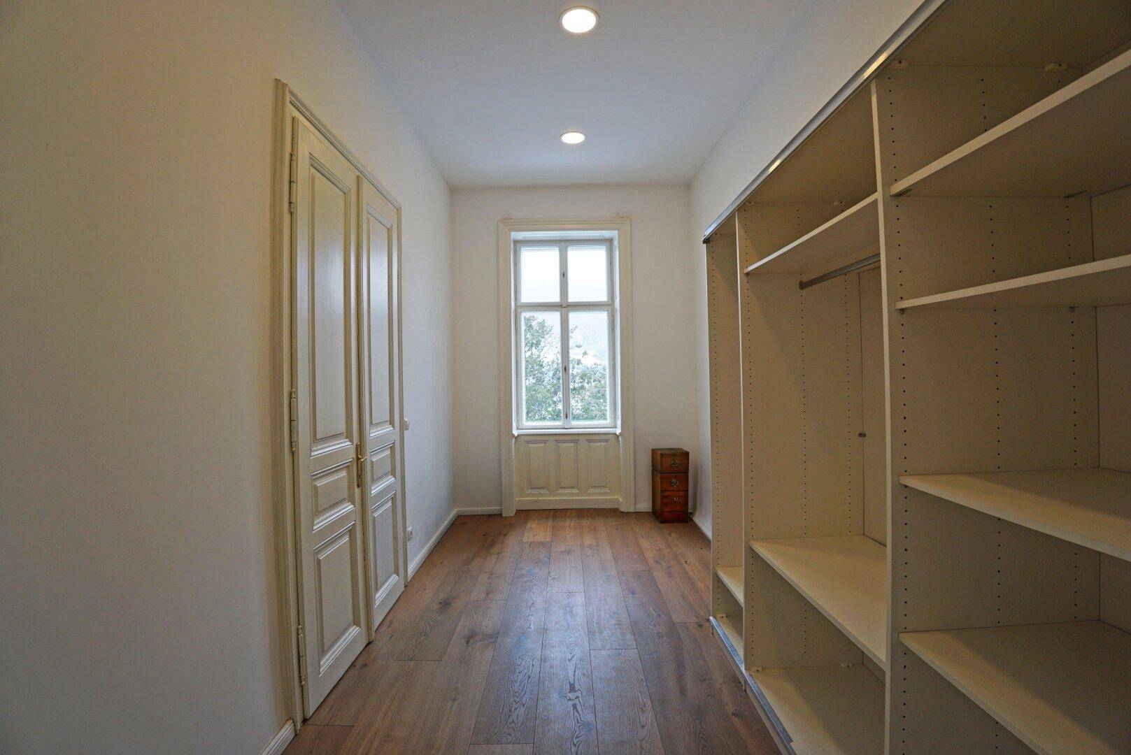Praktischer Ankleidebereich mit Einbauschränken und Fenster, ideal für Kleideraufbewahrung.