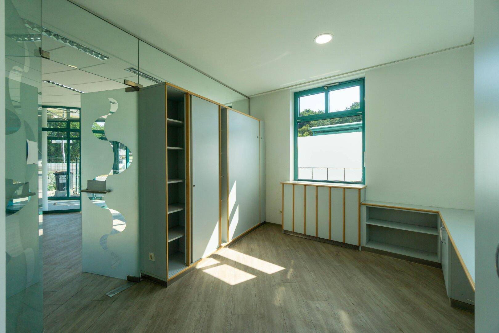 Büroraum mit Einbauschränken, einem Fenster und viel natürlichem Licht durch die großen Fenster.