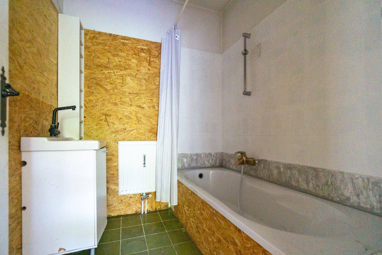 Badezimmer mit Badewanne und Waschbecken, das eine umfassende Renovierung benötigt.