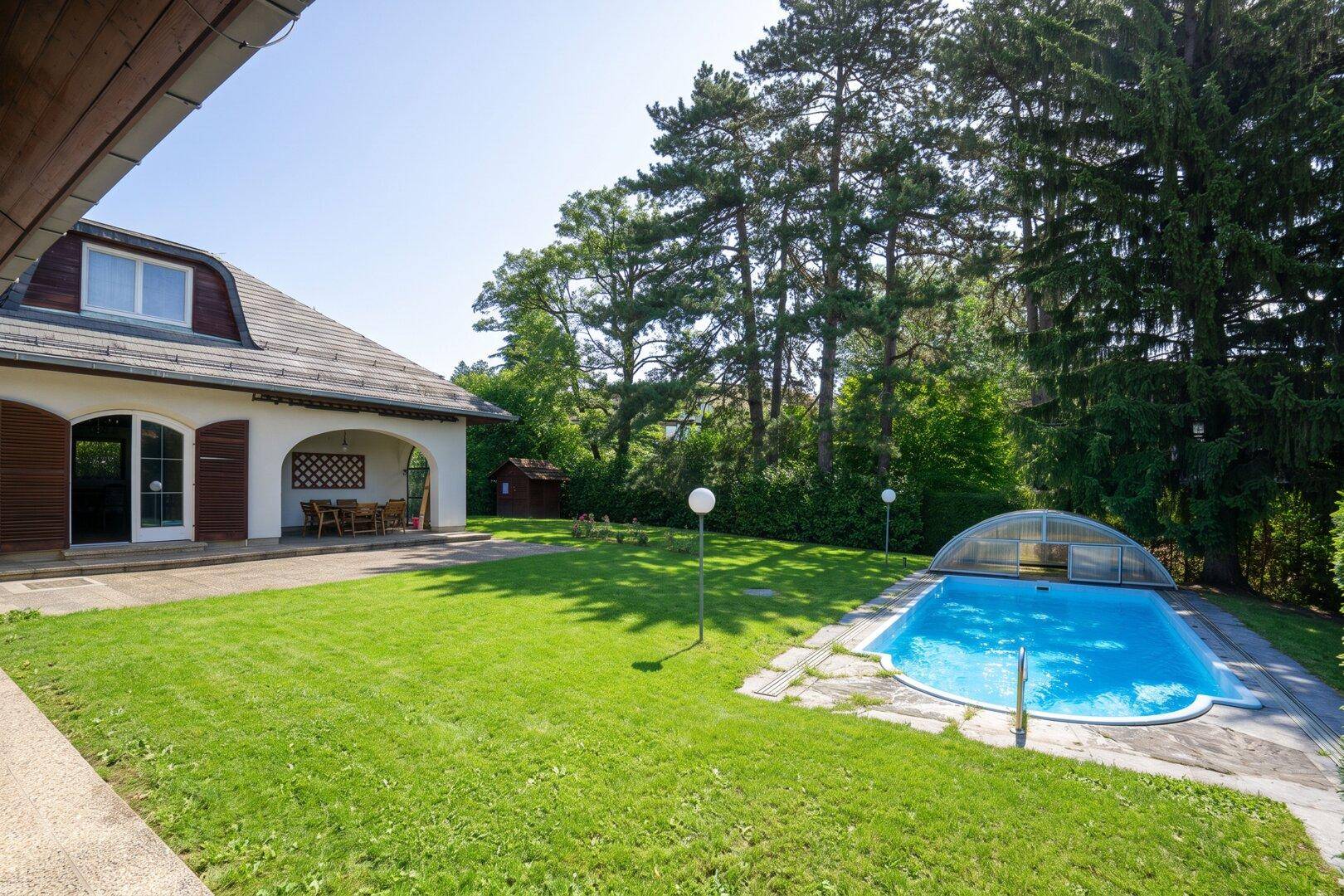 Großer, gepflegter Garten mit Rasenfläche, Pool und altem Baumbestand.