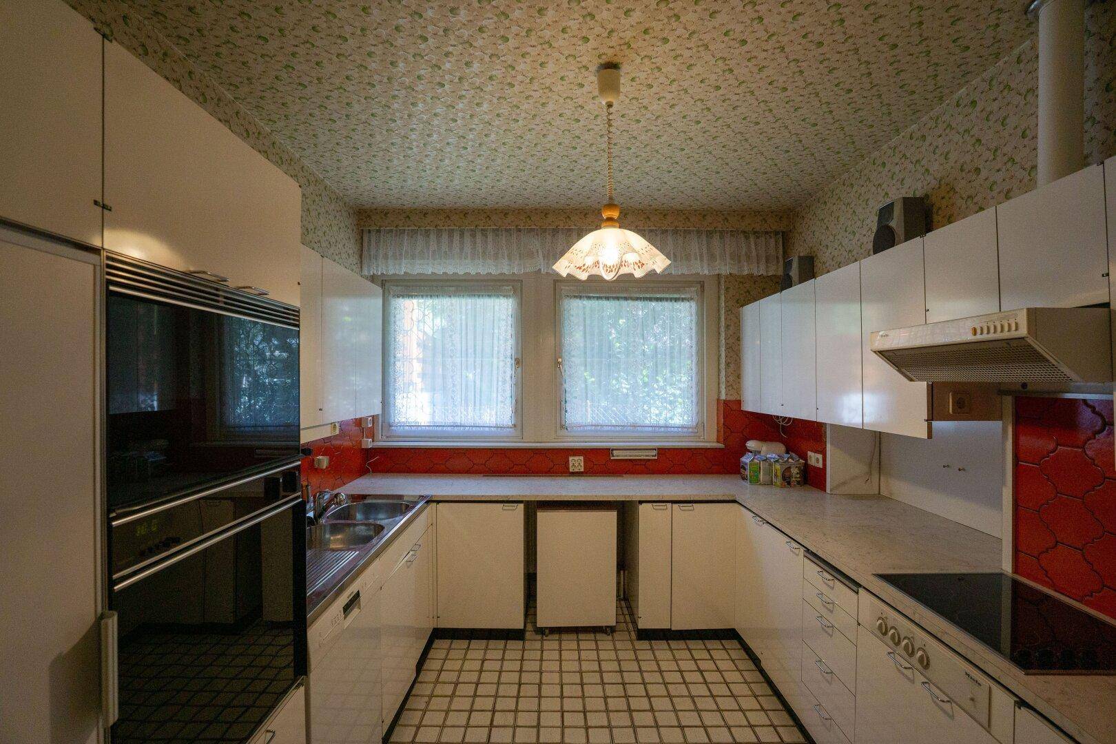 Originale Küche mit weißen Schränken, roten Fliesen und kariertem Boden.