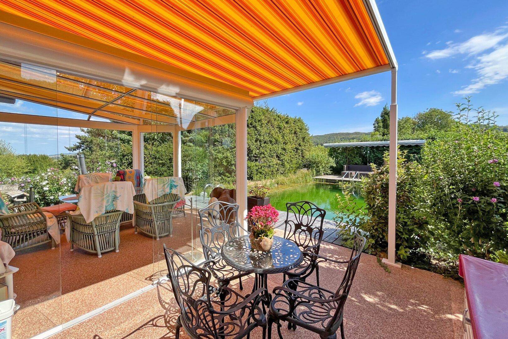 Sonniger Terrassenbereich mit schmiedeeisernen Möbeln und direktem Zugang zum Wintergarten.