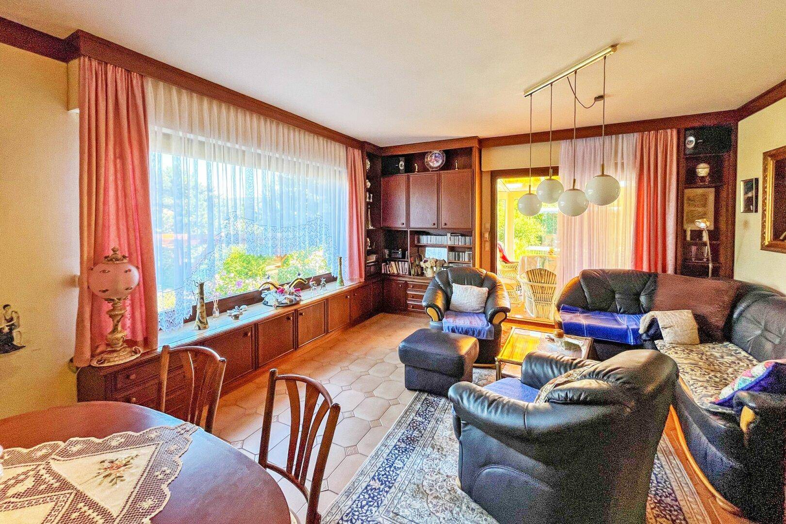 Geräumiger Wohn-Essbereich mit großen Fenstern, Ledermöbeln und Zugang zur Terrasse.