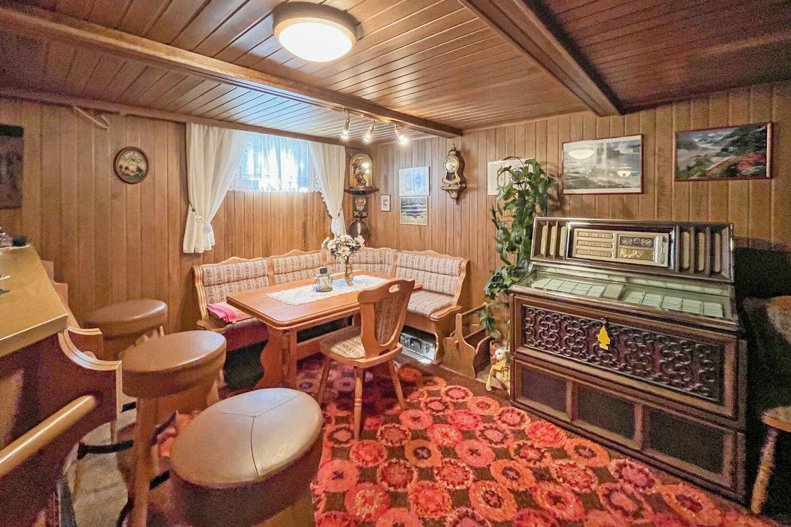 Gemütlicher Hobbyraum im Keller mit Holzvertäfelung, Sitzecke und Jukebox.