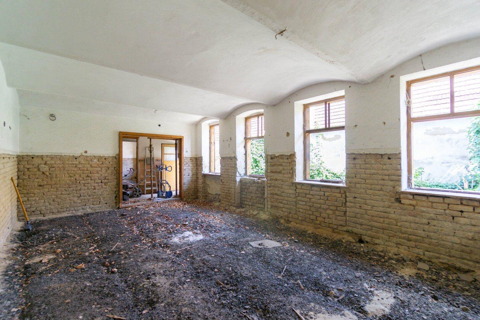 Großer Raum in Renovierung mit freigelegten Ziegelwänden und gewölbter Decke.